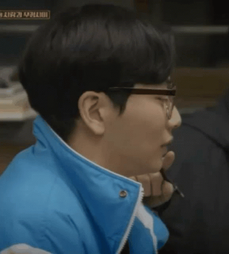 A Man Wearing Glasses And A Blue Jacket Has A Sign In The Background That Says ' A ' On It GIF