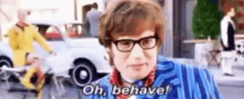 A Man Wearing Glasses And A Blue Jacket Is Standing In Front Of A Car And Saying `` Oh , Behave ! '' GIF