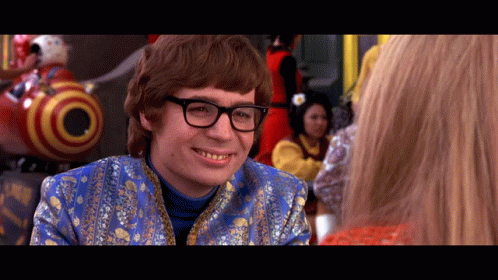 A Man Wearing Glasses And A Blue Jacket Smiles GIF