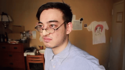 A Man Wearing Glasses And A Blue Shirt Has A T-Shirt On The Wall With A Picture Of A Woman On It GIF
