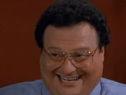 A Man Wearing Glasses And A Blue Shirt Is Laughing And Smiling . GIF