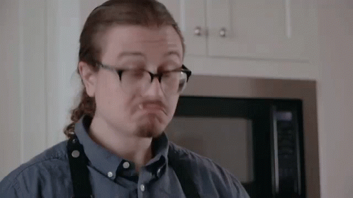 A Man Wearing Glasses And A Blue Shirt Is Making A Funny Face In Front Of A Microwave . GIF
