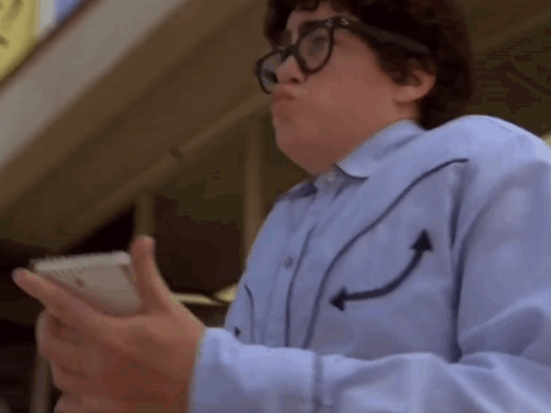 A Man Wearing Glasses And A Blue Shirt With Arrows On The Sleeves Is Holding A Cell Phone GIF