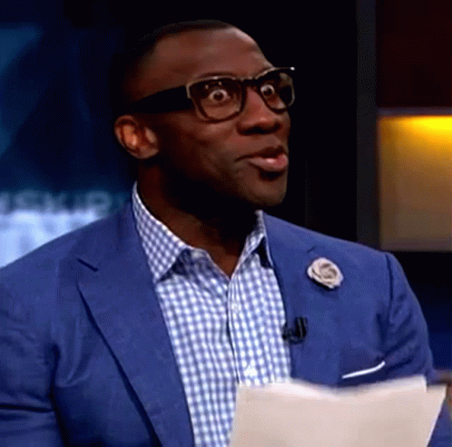 A Man Wearing Glasses And A Blue Suit Is Holding A Piece Of Paper In His Hand . GIF