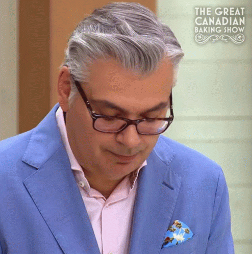 a man wearing glasses and a blue suit is on a great canadian baking show