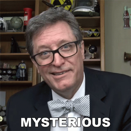 A Man Wearing Glasses And A Bow Tie Has The Word Mysterious Above His Head GIF