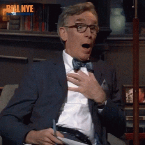 A Man Wearing Glasses And A Bow Tie Is Sitting On A Couch With His Mouth Open And The Words Bill Nye Behind Him GIF