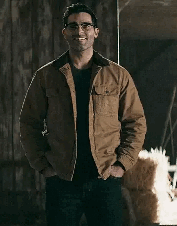 A Man Wearing Glasses And A Brown Jacket Is Standing In A Room With His Hands In His Pockets . GIF