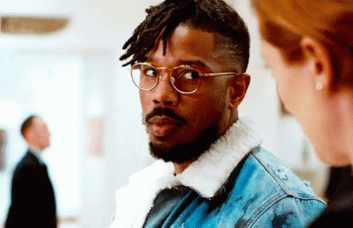 A Man Wearing Glasses And A Denim Jacket GIF