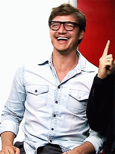 A Man Wearing Glasses And A Denim Shirt Is Laughing And Pointing Up GIF