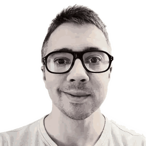 a man wearing glasses and a gray shirt smiles for the camera
