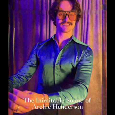 A Man Wearing Glasses And A Green Shirt With The Words The Inimitable Sound Of Archie Henderson On The Bottom GIF