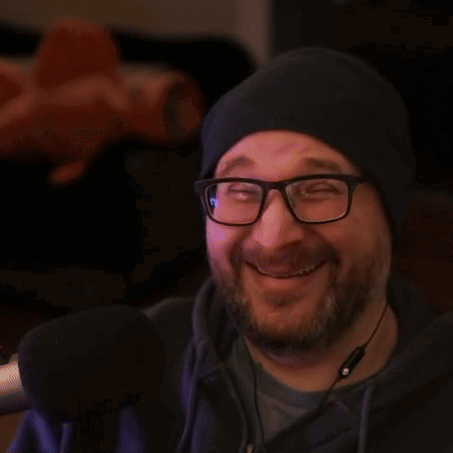 a man wearing glasses and a hat gives two thumbs up