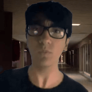 A Man Wearing Glasses And A Hat Is Looking At The Camera GIF