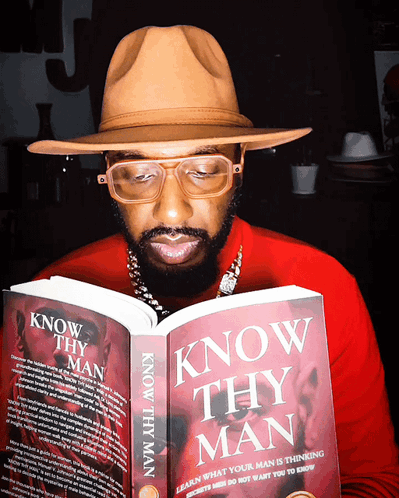 A Man Wearing Glasses And A Hat Is Reading A Book Titled Know Thy Man GIF
