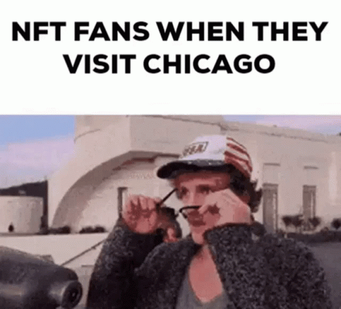 A Man Wearing Glasses And A Hat Is Standing In Front Of A Building And Looking At His Glasses . GIF
