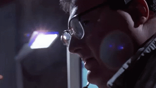 a man wearing glasses and a headset is looking down