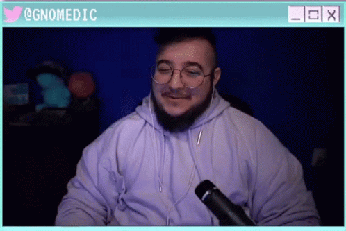 a man wearing glasses and a hoodie is sitting in front of a microphone with a twitter icon above him