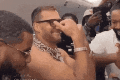 A Man Wearing Glasses And A Leopard Print Scarf Is Covering His Nose . GIF