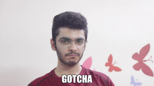 A Man Wearing Glasses And A Maroon Shirt With Gotcha Written On It GIF