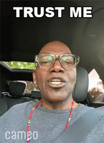 A Man Wearing Glasses And A Necklace Is Sitting In A Car With The Words Trust Me Above Him GIF