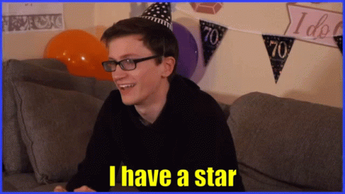 A Man Wearing Glasses And A Party Hat Is Sitting On A Couch And Says I Have A Star GIF