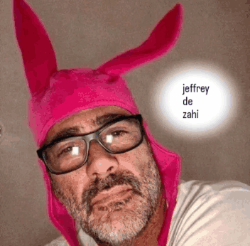 A Man Wearing Glasses And A Pink Hat With The Name Jeffrey De Zahi Written On It GIF