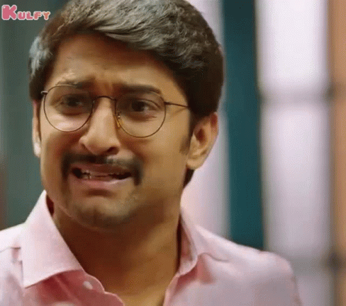 A Man Wearing Glasses And A Pink Shirt Making A Funny Face . GIF
