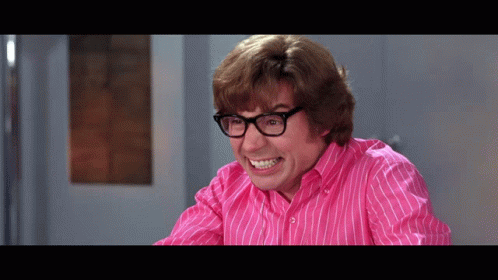 A Man Wearing Glasses And A Pink Striped Shirt Is Making A Funny Face GIF
