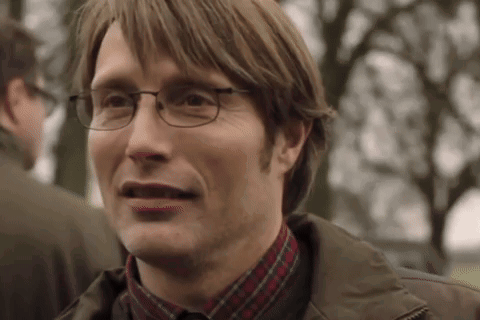 A Man Wearing Glasses And A Plaid Shirt Is Smiling And Making A Funny Face . GIF