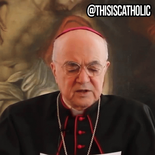A Man Wearing Glasses And A Purple Hat Stands In Front Of A Painting With The Caption " @Thisiscatholic " GIF