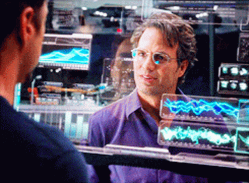 A Man Wearing Glasses And A Purple Shirt Is Looking At Another Man GIF