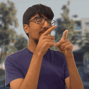 A Man Wearing Glasses And A Purple Shirt Is Pointing GIF