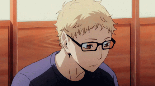 A Man Wearing Glasses And A Purple Shirt Is Sitting In Front Of A Window GIF