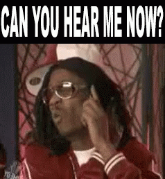 A Man Wearing Glasses And A Red Jacket Is Talking On A Cell Phone And Asking Can You Hear Me Now . GIF