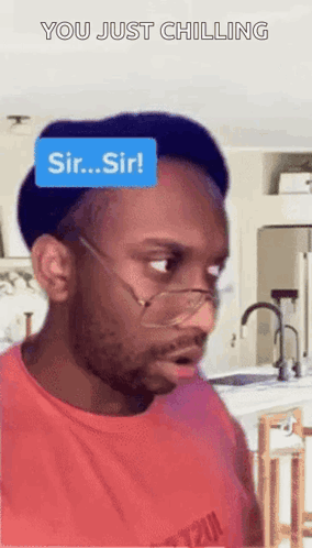 A Man Wearing Glasses And A Red Shirt With A Blue Sticker On His Head That Says Sir Sir GIF