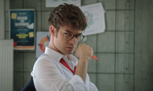 A Man Wearing Glasses And A Red Tie Holds A Pen GIF