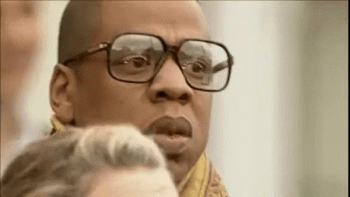 A Man Wearing Glasses And A Scarf Is Looking At Something . GIF