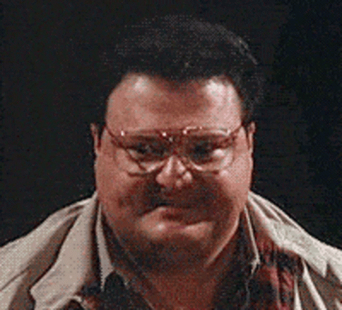 A Man Wearing Glasses And A Scarf Looks At The Camera GIF