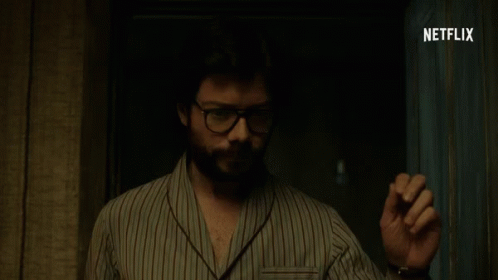 A Man Wearing Glasses And A Striped Shirt Is Standing In A Dark Room With Netflix Written On The Bottom GIF
