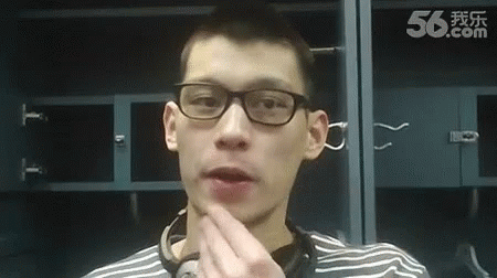 A Man Wearing Glasses And A Striped Shirt Is Standing In Front Of A Locker Room . GIF