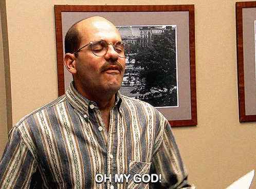 A Man Wearing Glasses And A Striped Shirt Says " Oh My God " GIF