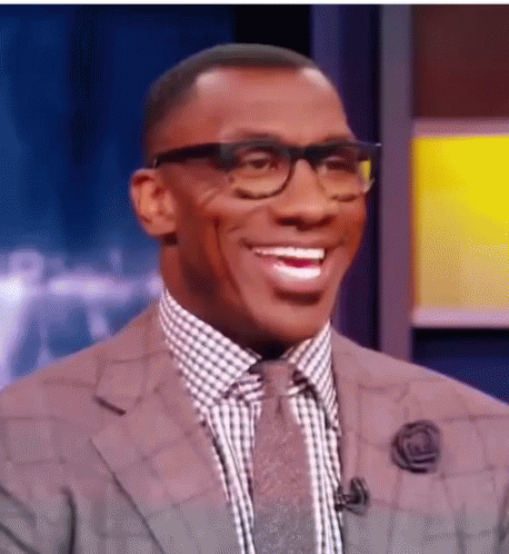 A Man Wearing Glasses And A Suit Is Smiling . GIF