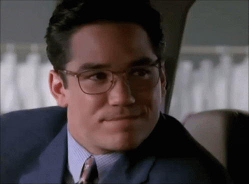 A Man Wearing Glasses And A Suit Looks At The Camera GIF