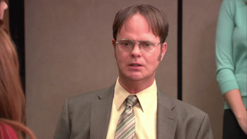 a man wearing glasses and a suit looks serious