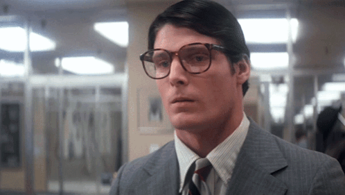 A Man Wearing Glasses And A Suit Looks To The Side GIF