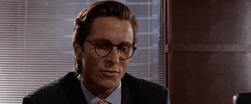 A Man Wearing Glasses And A Suit Looks To The Side GIF