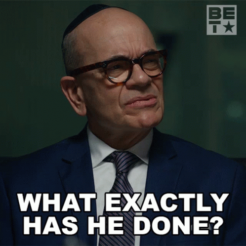 A Man Wearing Glasses And A Suit Says What Exactly Has He Done GIF
