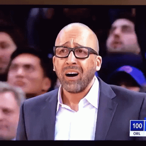 A Man Wearing Glasses And A Suit Stands In Front Of A Crowd With The Number 100 On The Bottom Right GIF