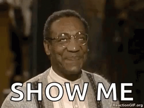 A Man Wearing Glasses And A Sweater Is Smiling And Saying `` Show Me '' . GIF
